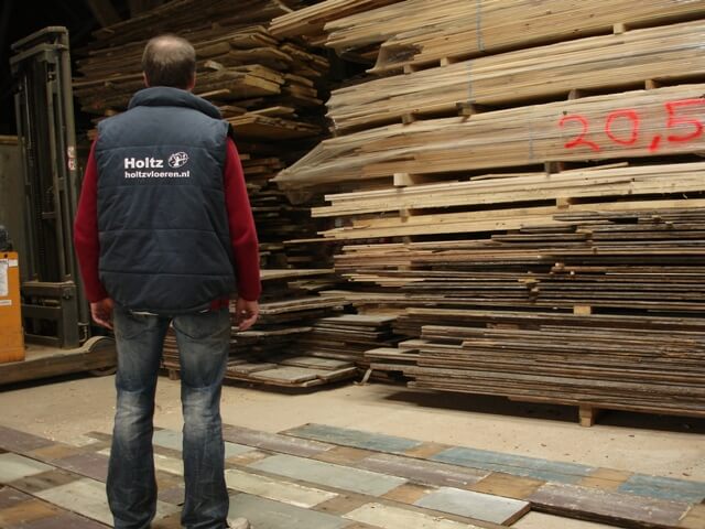 In de werkplaats worden oude grenen planken uitgezocht op kleur en breedte voor plaatsing in Amsterdam bij bekende Nederlander